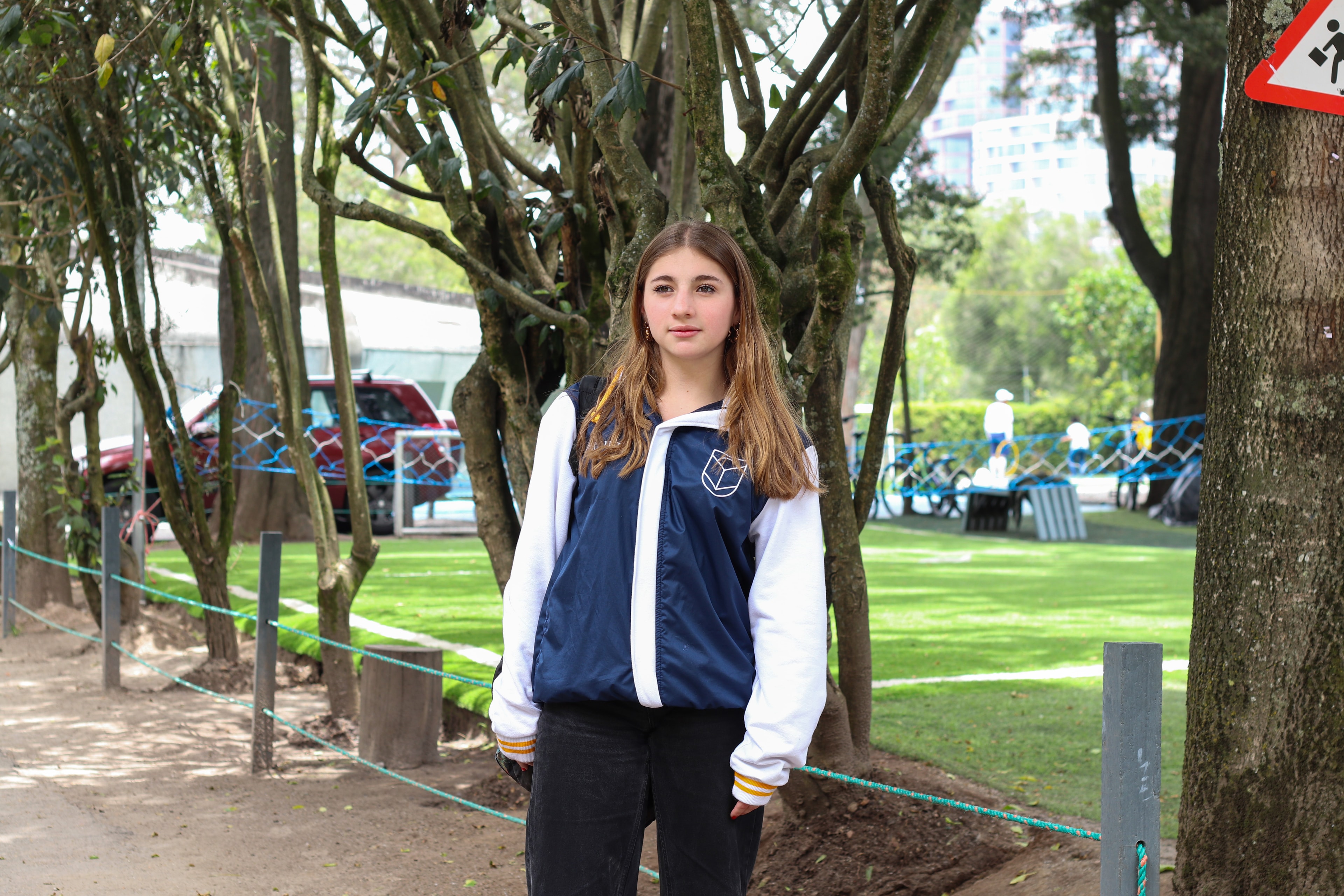 Estudiante de Comuna con la chaqueta institucional en los jardines del Parque La Carolina