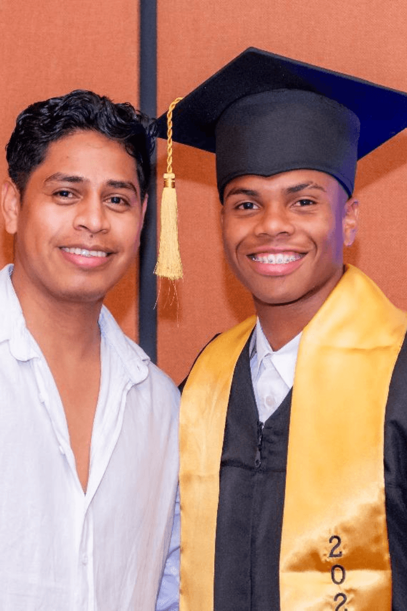 Graduado con toga y estola dorada junto a un familiar