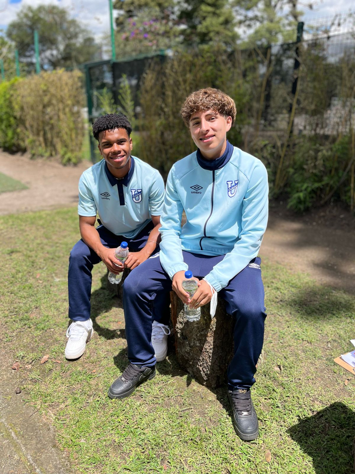 Dos jóvenes atletas de la Universidad Católica sentados en un jardín de la residencia